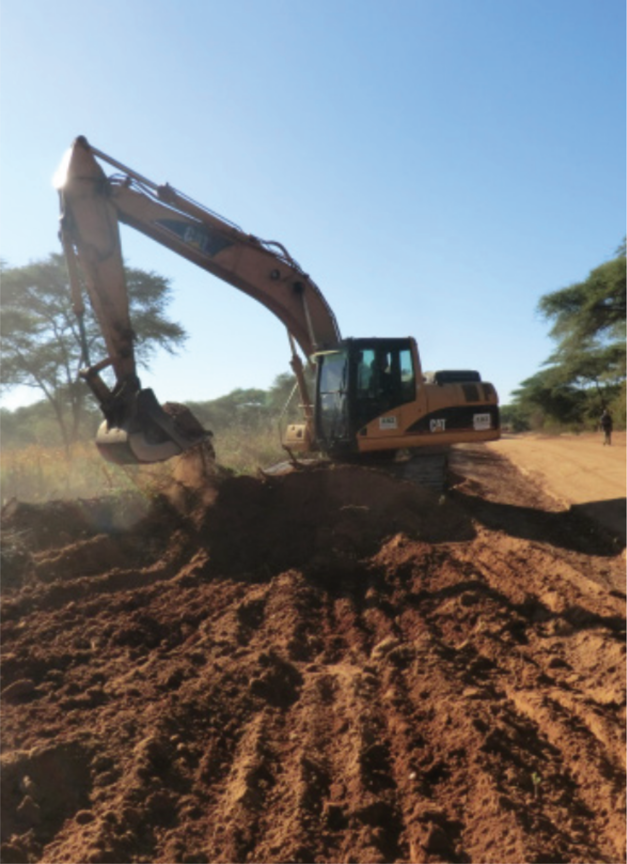 Excavator performing earthworks in red soil