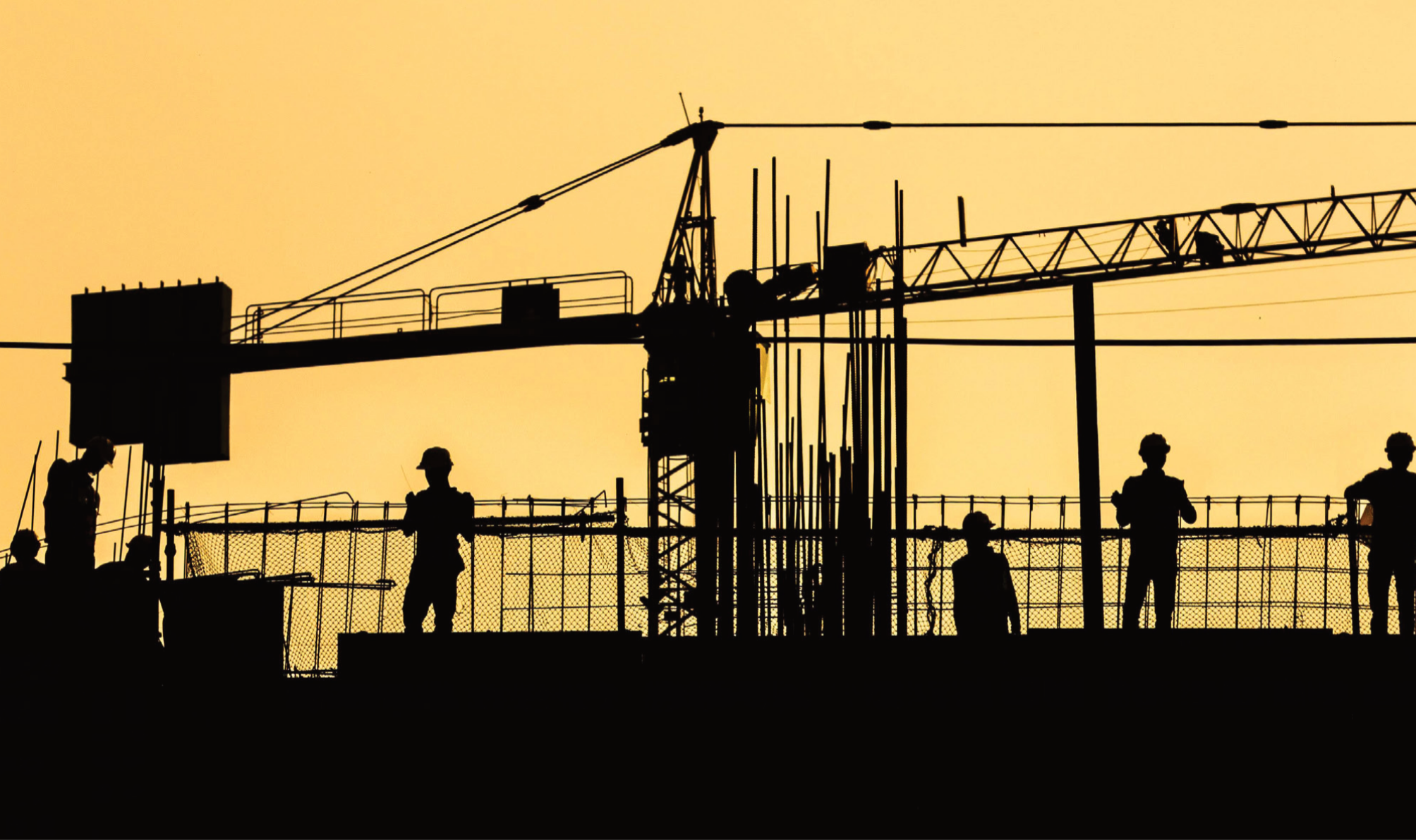 Construction workers at sunset with crane silhouette